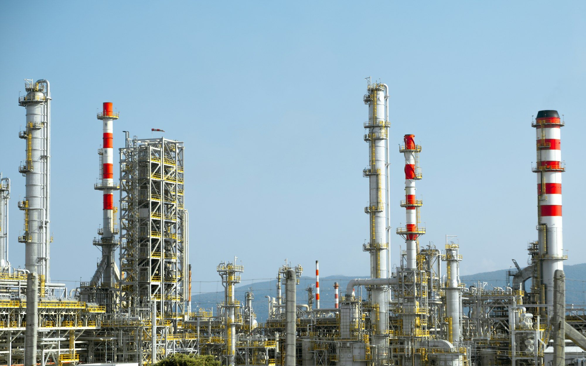 Refinery processing units and flare stacks against a blue sky